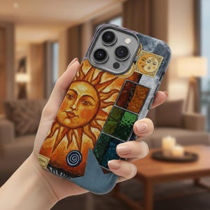 Pode incluir: Uma capa de telefone com um design vibrante de sol com um rosto sorridente, irradiando tons de laranja e amarelo. A capa também inclui um design de lua e uma série de quadrados coloridos. A capa tem uma pega azul semelhante a couro.