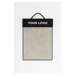 Puede incluir: Una muestra de tela con un encabezado negro con el texto "YOUR LOGO" en blanco. La tela es de color beige claro con una apariencia texturizada, enmarcada por un borde negro. Un asa negra está unida al encabezado.