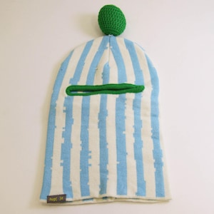 Könnte beinhalten: Eine blau-weiß gestreifte Sturmhaube mit grün gestricktem Rand um die Augenöffnung und einem grün gestrickten Ball oben. Die Sturmhaube hat unten den Text "hug{ }z".