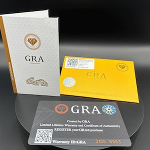 May include: A set of GRA documents, including a Moissanite Report, warranty card, and certificate of authenticity. The documents feature the GRA logo, QR codes, and text such as "Limited Lifetime Warranty" and "Register your GRA purchase."
