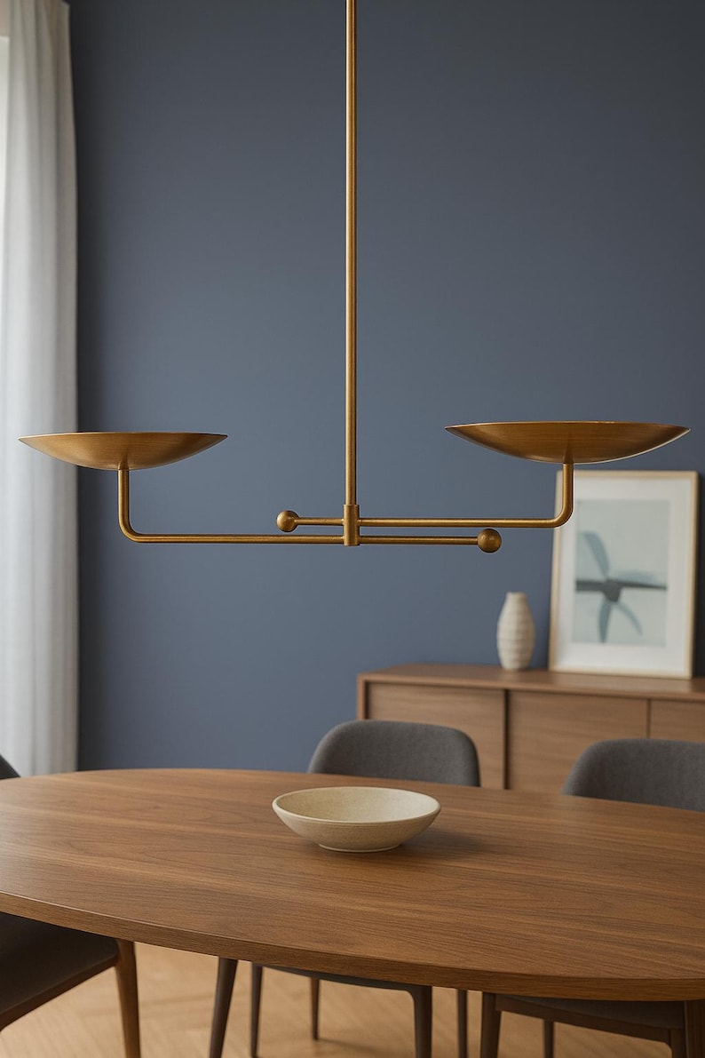 Modern brass linear chandelier with two dish-shaped shades hanging above a minimalist gray and white bedroom interior
Handmade brass pendant light fixture with dual disc shades in a modern bedroom with neutral décor
Luxury brushed brass two-arm linear chandelier installed above a bed in a contemporary minimalist room
Mid century modern brass ceiling light with two flat dome shades illuminating a cozy bedroom interior