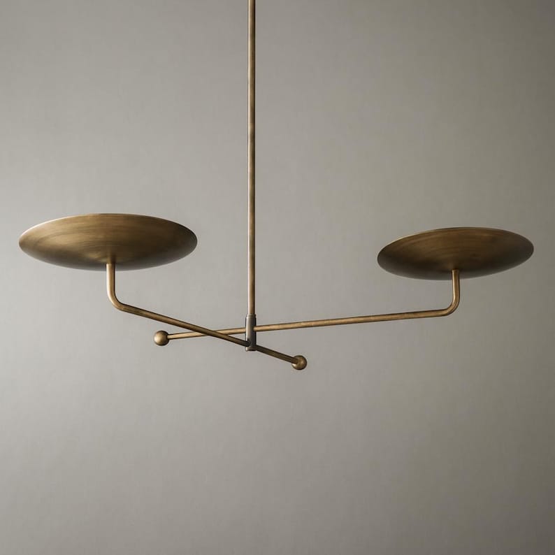 Modern brass linear chandelier with two dish-shaped shades hanging above a minimalist gray and white bedroom interior
Handmade brass pendant light fixture with dual disc shades in a modern bedroom with neutral décor
Luxury brushed brass two-arm linear chandelier installed above a bed in a contemporary minimalist room
Mid century modern brass ceiling light with two flat dome shades illuminating a cozy bedroom interior