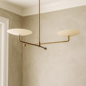 Modern brass linear chandelier with two dish-shaped shades hanging above a minimalist gray and white bedroom interior
Handmade brass pendant light fixture with dual disc shades in a modern bedroom with neutral décor
Luxury brushed brass two-arm linear chandelier installed above a bed in a contemporary minimalist room
Mid century modern brass ceiling light with two flat dome shades illuminating a cozy bedroom interior