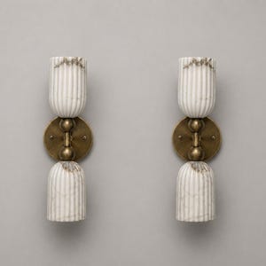 Pode incluir: Duas arandelas de parede combinando. Cada arandela apresenta um design de mármore branco com nervuras verticais e detalhes em latão. As arandelas têm uma placa de latão arredondada e uma forma cilíndrica. As arandelas são projetadas para montagem na parede.