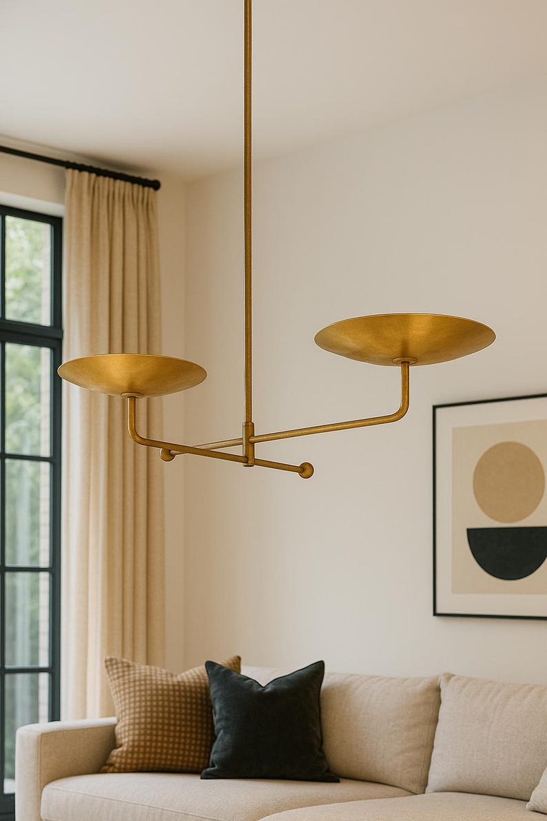 Modern brass linear chandelier with two dish-shaped shades hanging above a minimalist gray and white bedroom interior
Handmade brass pendant light fixture with dual disc shades in a modern bedroom with neutral décor
Luxury brushed brass two-arm linear chandelier installed above a bed in a contemporary minimalist room
Mid century modern brass ceiling light with two flat dome shades illuminating a cozy bedroom interior