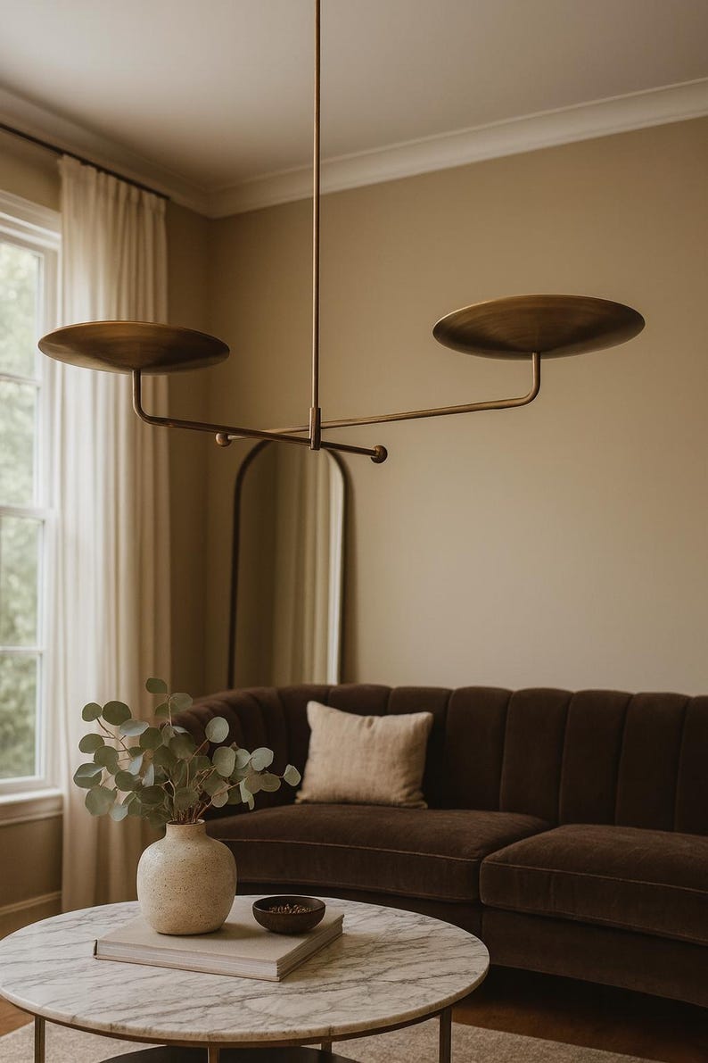 Modern brass linear chandelier with two dish-shaped shades hanging above a minimalist gray and white bedroom interior
Handmade brass pendant light fixture with dual disc shades in a modern bedroom with neutral décor
Luxury brushed brass two-arm linear chandelier installed above a bed in a contemporary minimalist room
Mid century modern brass ceiling light with two flat dome shades illuminating a cozy bedroom interior