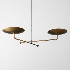Modern brass linear chandelier with two dish-shaped shades hanging above a minimalist gray and white bedroom interior
Handmade brass pendant light fixture with dual disc shades in a modern bedroom with neutral décor
Luxury brushed brass two-arm linear chandelier installed above a bed in a contemporary minimalist room
Mid century modern brass ceiling light with two flat dome shades illuminating a cozy bedroom interior