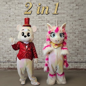 May include: Two full-body costumes: a white bear in a red sequined jacket and a unicorn with pink accents. The text "2 in 1" is displayed in gold script above the costumes. The costumes are iridescent and stand in front of a brick wall.