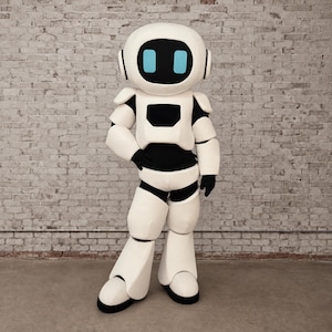 Op de afbeelding: Een volledig robot-mascottekostuum met een grote, ronde witte kop, een zwart voorpaneel en twee rechthoekige lichtblauwe ogen. Het pak is voorzien van witte pantserplaten over een zwarte basislaag die de romp, armen en benen bedekken.
