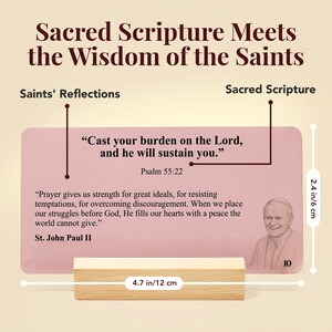 K&ouml;nnte beinhalten: Eine rechteckige rosa Karte mit dem Text 'Cast your burden on the Lord, and he will sustain you.' Psalm 55:22 und einem Zitat von Johannes Paul II. Die Karte misst 6 cm mal 12 cm und steht in einem hellen Holzblockst&auml;nder.