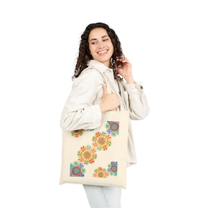 Puede incluir: Bolso tote de color crema con un patrón repetido de diseños florales coloridos. Las flores tienen una mezcla de tonos naranja, amarillo, verde y azul. La bolsa está hecha de una tela resistente y tiene una forma rectangular simple.