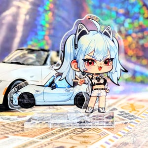 May include: A clear acrylic anime-style figure of a girl with light blue hair, red eyes, and a white outfit, standing in front of a white sports car. The figure is on a clear base. The background has a holographic effect.