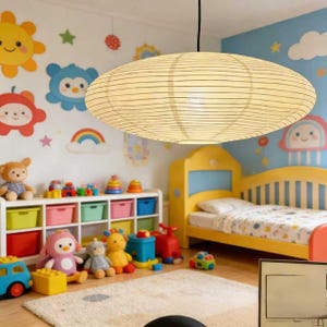 以下が含まれることがあります： 黒い水平線が入った、楕円形のクリーム色の紙製ペンダントライトが子供部屋に吊り下げられています。 部屋には黄色のベッド、カラフルなおもちゃ、壁の装飾があり、遊び心のある雰囲気を作り出しています。