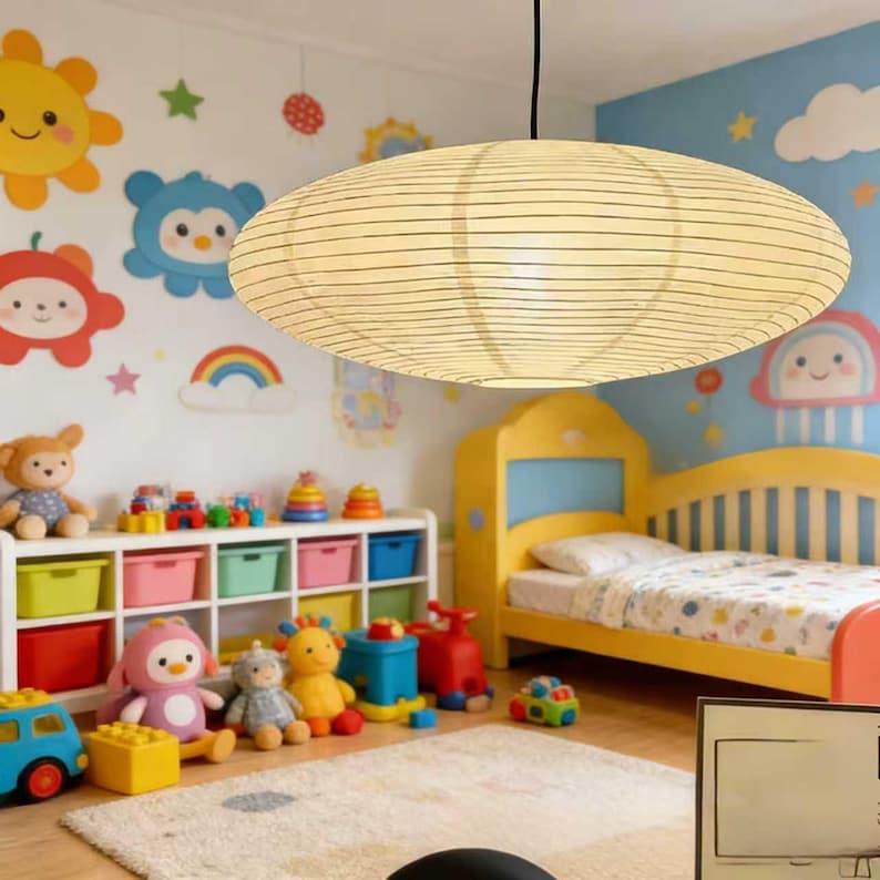 以下が含まれることがあります： 黒い水平線が入った、楕円形のクリーム色の紙製ペンダントライトが子供部屋に吊り下げられています。 部屋には黄色のベッド、カラフルなおもちゃ、壁の装飾があり、遊び心のある雰囲気を作り出しています。