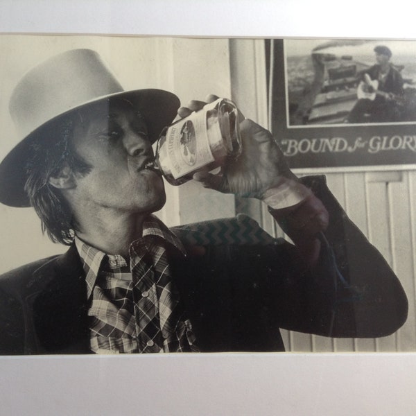 Photograph of David Carradine.   Framed 1970's PRINT.  Drinking Southern Comfort in front of a Bound for Glory Poster.