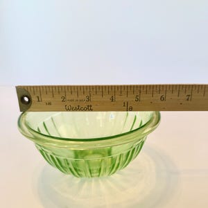 May include: A small, light green glass bowl with vertical ribbed detailing. The bowl is approximately 5 inches in diameter. A wooden ruler is placed across the top of the bowl. The text "MADE IN U.S.A." and "Westcott" are visible on the ruler.