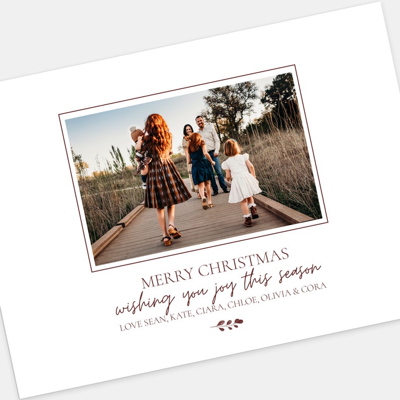 Puede incluir: Una tarjeta de Navidad con una familia de cinco personas caminando por un sendero de madera en un &aacute;rea boscosa. La tarjeta tiene el texto "Merry Christmas wishing you joy this season Love Sean, Kate, Ciara, Chloe, Olivia & Cora" en una fuente color burdeos.