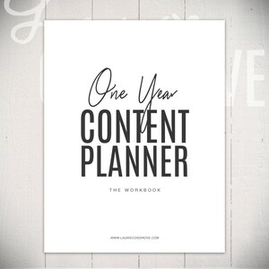 May include: A white sheet of paper with black text that reads "One Year Content Planner The Workbook www.lauriecoshgrove.com".