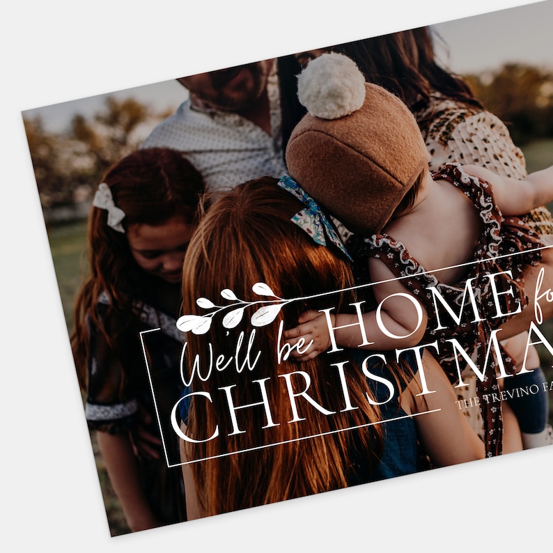 Puede incluir: Una familia de cuatro, incluyendo un ni&ntilde;o peque&ntilde;o, se abrazan en un c&aacute;lido abrazo. La imagen est&aacute; ambientada en un fondo de bosque verde borroso. El texto "We'll be home for Christmas" est&aacute; superpuesto a la imagen en una fuente blanca cursiva con un elemento floral decorativo.