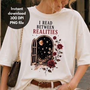 May include: An off-white t-shirt featuring the black and red text I READ BETWEEN REALITIES above a graphic of an open arched window looking out into a starry night sky with a planet, surrounded by a climbing vine of red roses and green leaves.