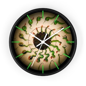 May include: A round wall clock with a black frame. The clock face features a vintage illustration of green, snake-like creatures radiating from a central point. The clock hands are white, and the hour markers are green.