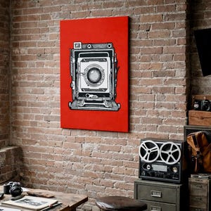 May include: A black and white vintage camera illustration on a red canvas, mounted on a brick wall. The image is part of a photography-themed decor, with other cameras and equipment visible in the background.