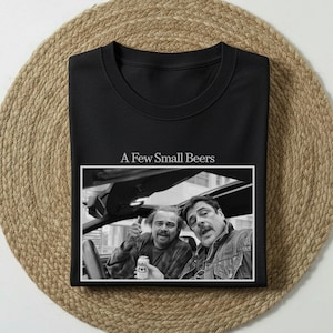 May include: Black crew neck sweatshirt with the text "A Few Small Beers" above a black and white photo of two men in a car. One man is holding a beer can and giving a thumbs up.