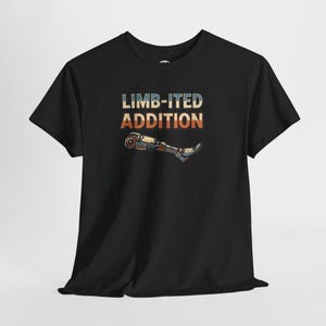 Puede incluir: Camiseta negra con el texto "LIMB-ITED ADDITION" en blanco, naranja y azul. El diseño incluye un gráfico de una pierna protésica de estilo retro. La camiseta está hecha de un material suave.