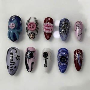 May include: A set of ten artificial nails with various designs. The designs include an octopus, a button spider, the text "Welcome Home!", a spiderweb, a swirl, the name "Coraline", a black cat, a key, a circular design, and a dragonfly.