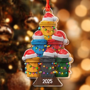 May include: A Christmas tree ornament featuring a stack of colorful trash cans, each adorned with a Santa hat and string lights. The ornament has a red ribbon for hanging and the year 2025 is displayed at the bottom.