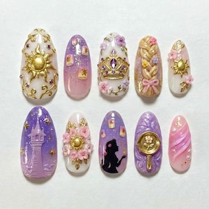 May include: A set of ten intricately designed artificial nails. Each nail features a different design, including a golden sun, a crown, a tower, and a silhouette, with various colors like gold, purple, pink, and white. The nails are decorated with 3D elements.