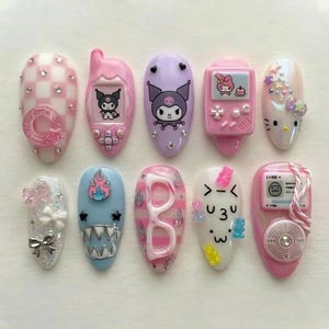 Könnte beinhalten: Zehn künstliche Fingernägel mit vielfältigen Designs, darunter Cartoonfiguren, geometrische Muster und 3D-Verzierungen. Die Nägel zeigen eine Reihe von Farben und Nageldesign-Techniken und bieten eine verspielte und kreative Ästhetik.