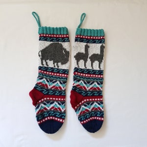 May include: Two knitted Christmas stockings with a white background and colorful patterns. One stocking features a bison and the other features two llamas.