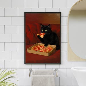 May include: A framed print featuring a black cat enjoying a slice of pizza from a cardboard box. The cat is sitting on a red couch. The pizza has pepperoni toppings.