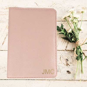 May include: A pale pink passport holder with the initials "JMC" embossed in gold.