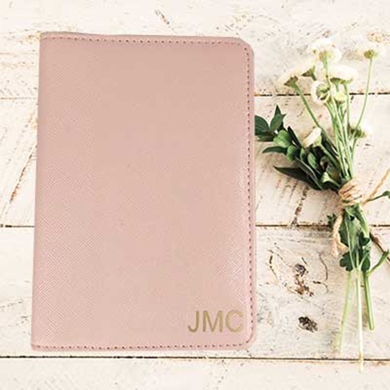 May include: A pale pink passport holder with the initials "JMC" embossed in gold.