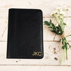 May include: A black leather notebook with gold lettering that reads "J.K.C."