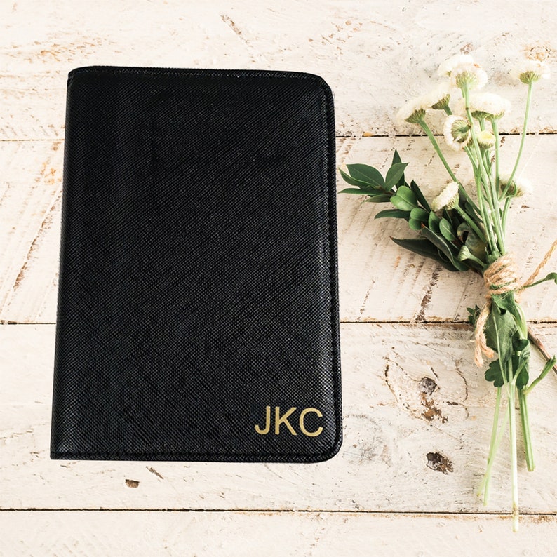 May include: A black leather notebook with gold lettering that reads "J.K.C."