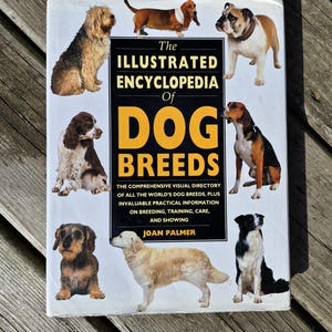 May include: The Illustrated Encyclopedia of Dog Breeds book cover. The cover features illustrations of various dog breeds surrounding the title text. The book includes information on breeding, training, care, and showing.