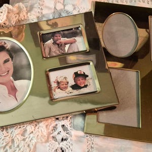 May include: Two gold-toned metal multi-opening picture frames. One frame features a large oval opening with a photo of a person and two smaller rectangular openings with photos. The second frame has one oval and three rectangular empty openings.
