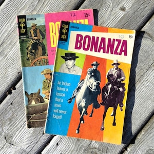 May include: A white ceramic mug with a black handle and the text "But First, Coffee" in a black, bold font. The mug is on a white surface.