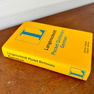 May include: A yellow Langenscheidt Pocket Dictionary for German, with the letter "L" in blue on the cover.