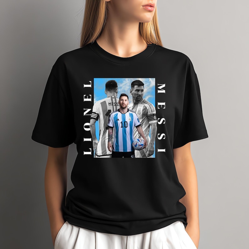 Puede incluir: Camiseta negra con un gr&aacute;fico de Lionel Messi con su uniforme de f&uacute;tbol, con las palabras "Lionel Messi" en texto vertical blanco. La imagen muestra a Messi en tres poses diferentes, sosteniendo un bal&oacute;n de f&uacute;tbol.