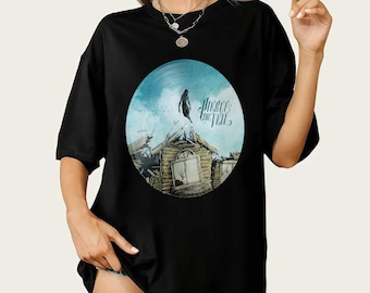 Peut inclure: T-shirt noir avec un motif circulaire représentant une personne sur un bâtiment, un ciel bleu et le texte "Collide With The Sky" et "Pierce The Veil". Le t-shirt a des manches courtes et un col rond.