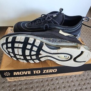 Puede incluir: Zapatillas deportivas negras con suelas blancas y una burbuja de aire visible. Las zapatillas est&aacute;n sobre una caja de cart&oacute;n con el texto "MOVE TO ZERO". Las zapatillas tienen cordones negros y un dise&ntilde;o de malla.