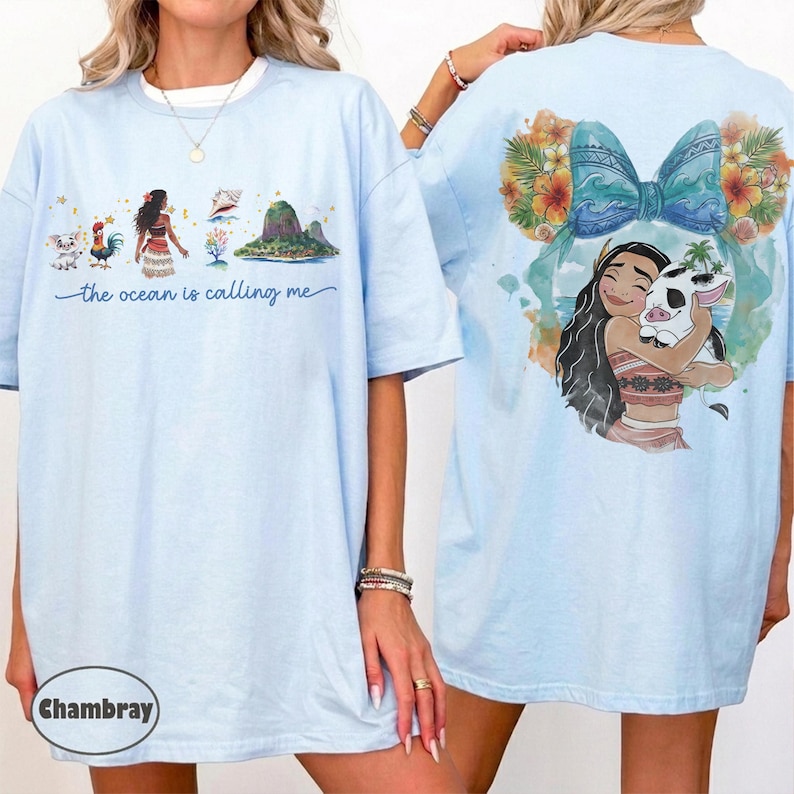 May include: Light blue t-shirts with a graphic print. The front features a cartoon illustration with the text "the ocean is calling me." The back displays a character hugging a pig, surrounded by floral accents.