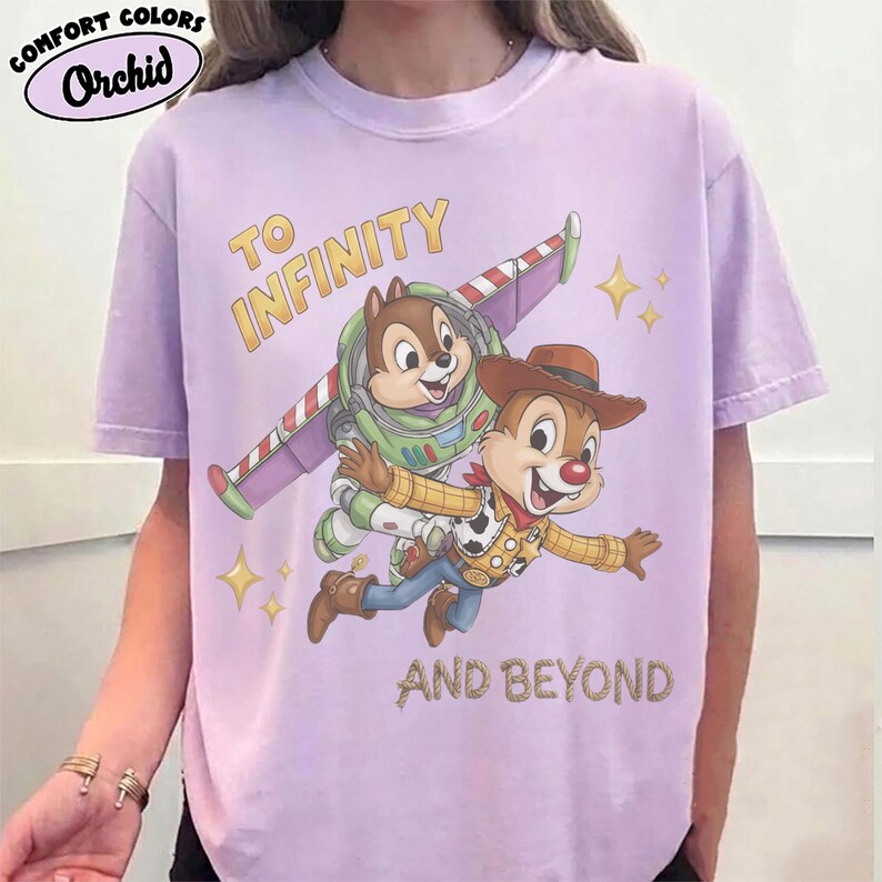 May include: A light purple t-shirt featuring a graphic of two chipmunks dressed as space and cowboy characters. One chipmunk wears a space suit with wings, and the other wears a cowboy hat and vest. The text reads TO INFINITY AND BEYOND.
