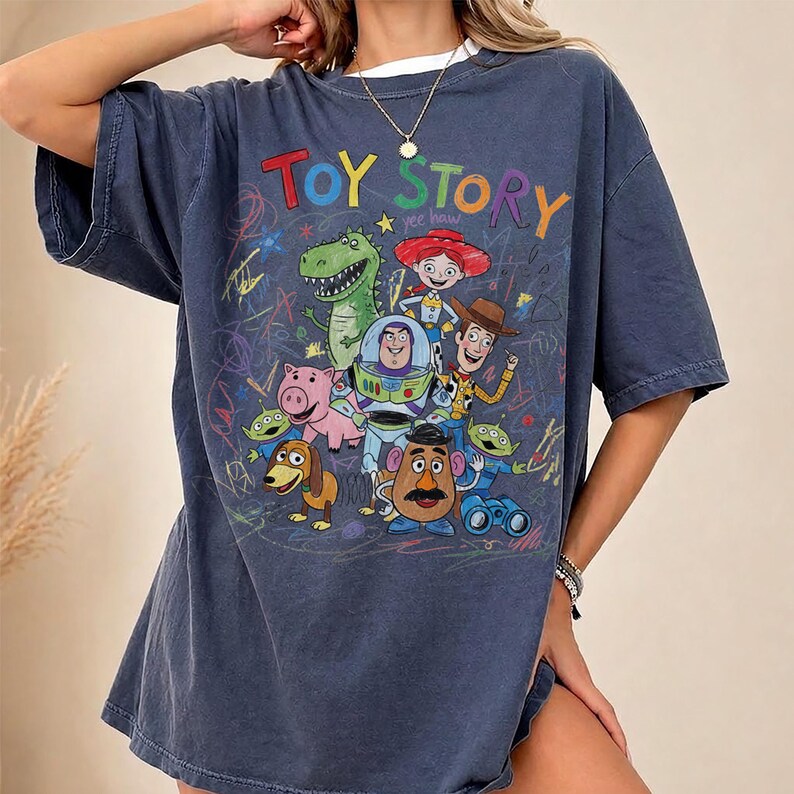 Puede incluir: Una camiseta azul marino con las palabras "TOY STORY" en letras coloridas y un gr&aacute;fico de personajes de la pel&iacute;cula animada. El dise&ntilde;o incluye a Woody, Buzz Lightyear, Rex y otros personajes.