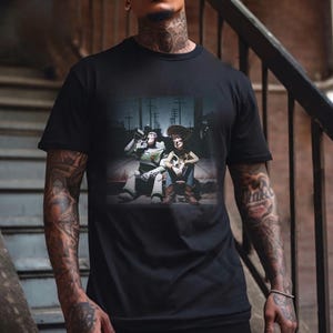 Puede incluir: Camiseta negra con un gr&aacute;fico de Buzz Lightyear y Woody de Toy Story. La imagen muestra a los personajes juntos, con Buzz bebiendo de una botella. El fondo representa una escena callejera.