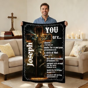 May include: Black blanket with a cross, lion, and knight graphic. The blanket has the name "Joseph" and the words "YOU are..." with Bible verses. The design is in shades of gold, black, and brown.
